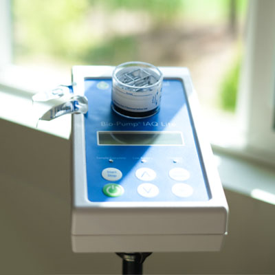 Air Sampling. Professional air sampling pump and cassette trapping mold spores in a residential living space for laboratory analysis.